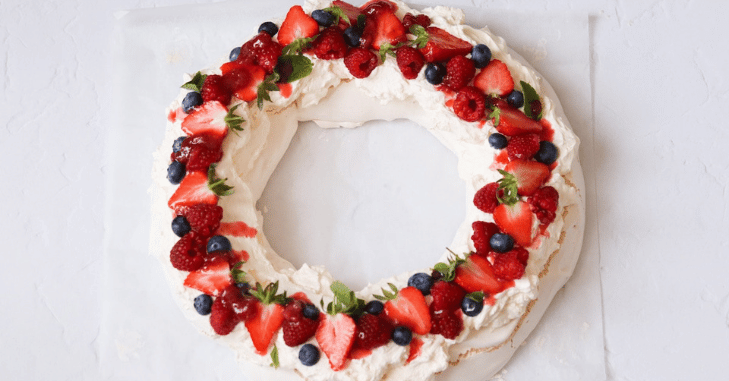 Finished pavlova topped with berries and dusted icing sugar